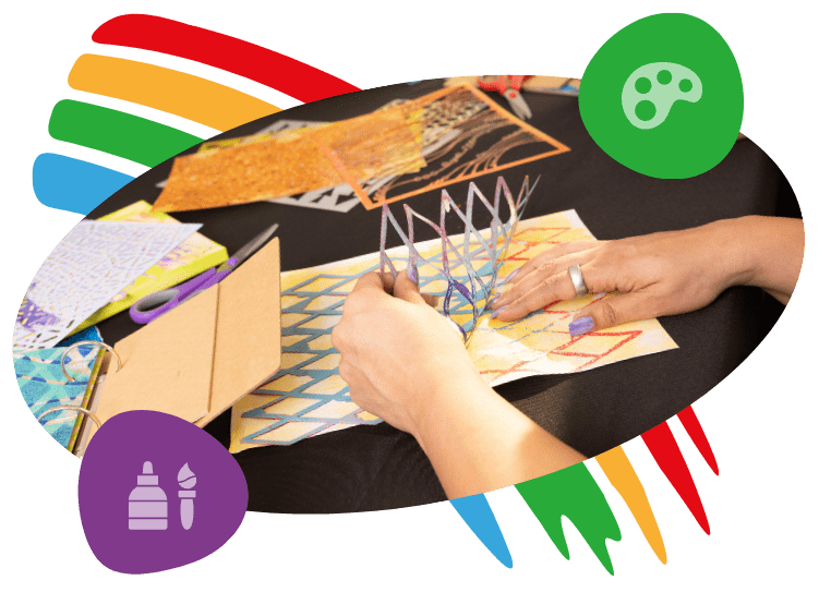 Creative Joy Collective Student's hands lifting a geometric paper stencil from a yellow and orange painted mixed media background.